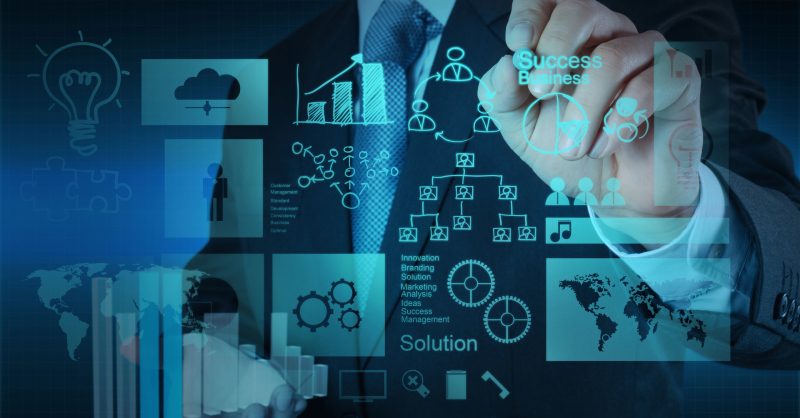 Dailyza Explores the New Era of Project Management Platforms Team collaborating around a digital project management dashboard on a large screen in a modern office
