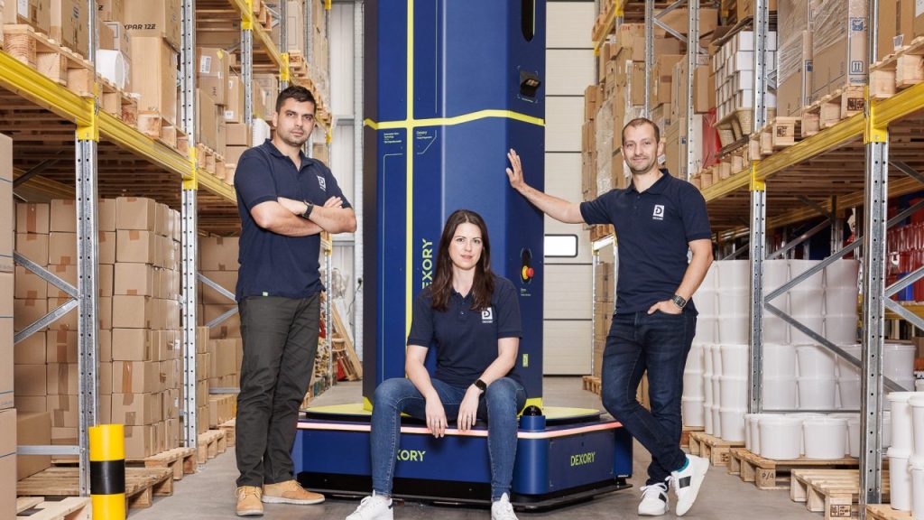 Dexory team posing together in a warehouse robotics environment